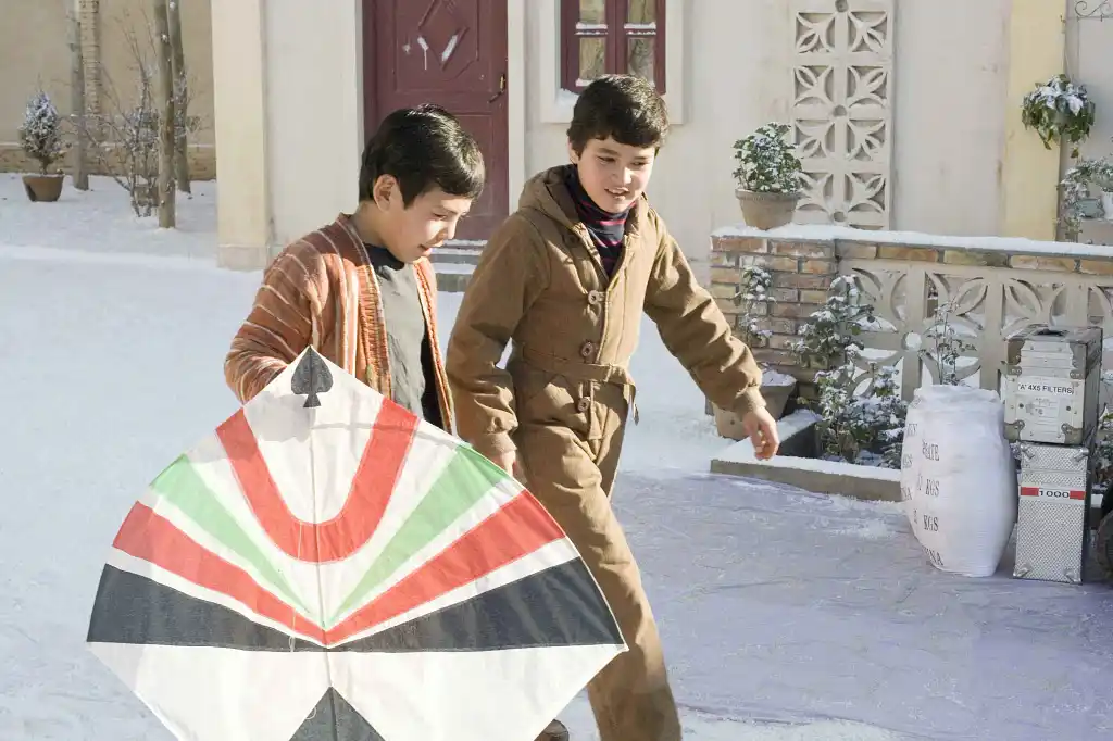 Amir and Hassan walk down the street with a kite in The Kite Runner