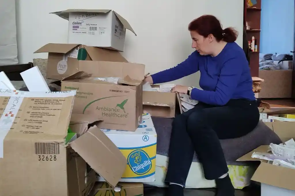 Anna sitting on boxes and sorting out a medical supplies deliver